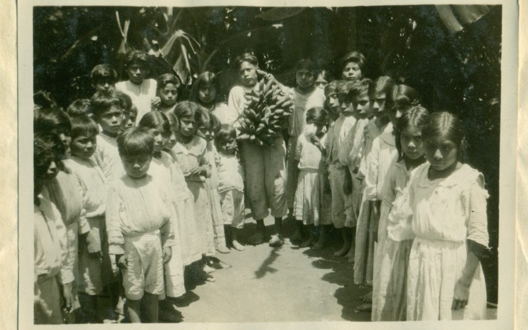 Alumnos contemplando un racimo de plátanos, producto del Huerto Escolar. 1931.